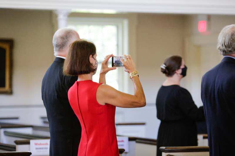 a woman in a red dress taking a picture of a man and woman in a church
