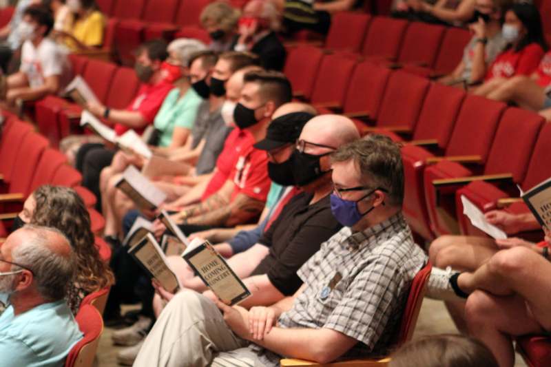 a group of people wearing face masks sitting in a theater