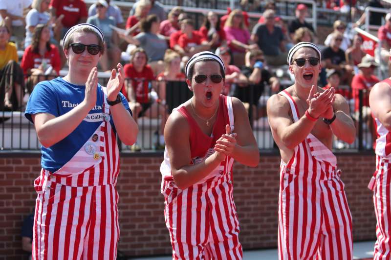 a group of people wearing striped overalls and standing in front of a crowd