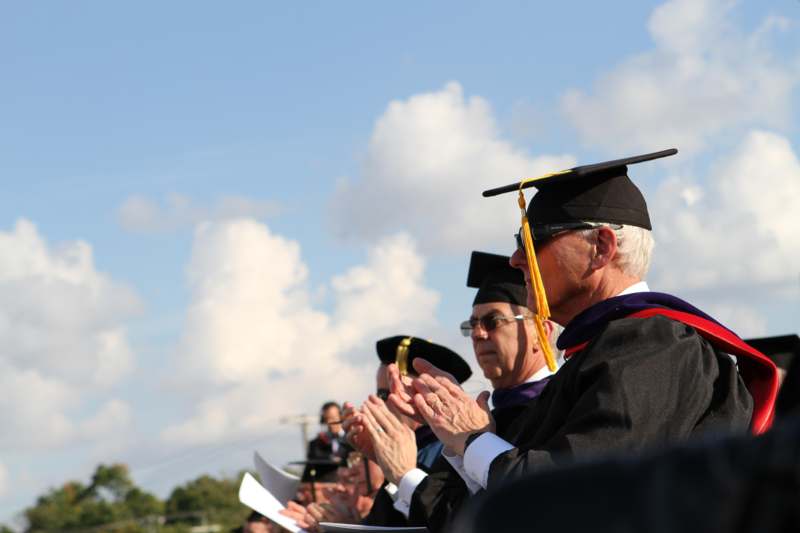 a group of people in graduation gowns and cap clapping