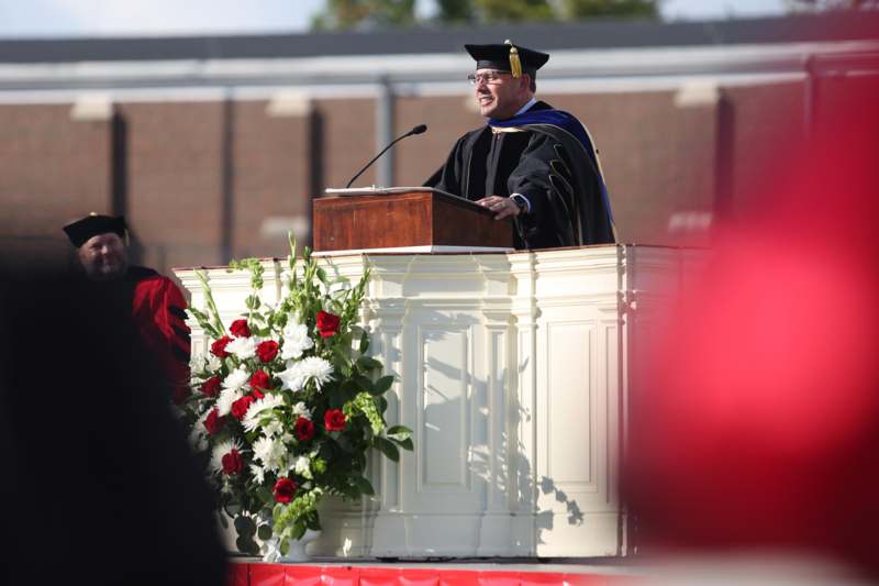 a man in a graduation gown and cap standing at a podium