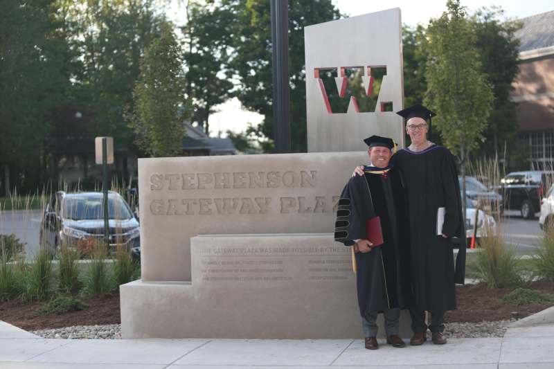 a man and woman in graduation gowns posing for a picture