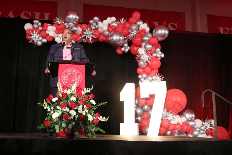 a man standing at a podium with a podium and balloons