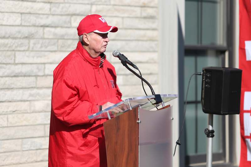 a man in red jacket standing at a podium