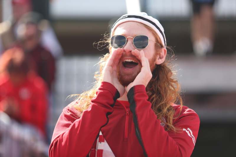 a man with long hair wearing sunglasses and red shirt with hands on his face