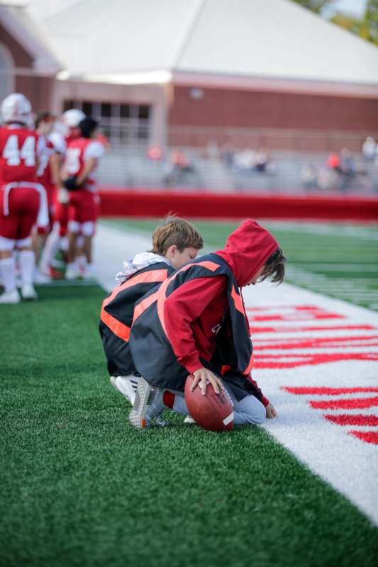 a boy kneeling on the ground with a football