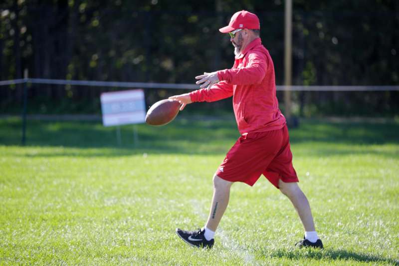 a man in red shirt and cap throwing a football