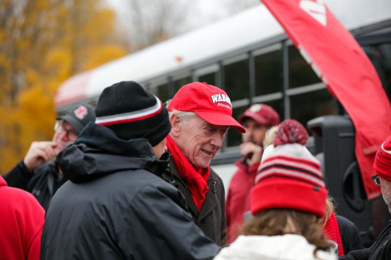 a man in red hat and red scarf talking to a group of people
