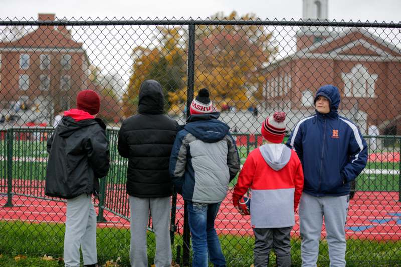 a group of people standing in front of a fence