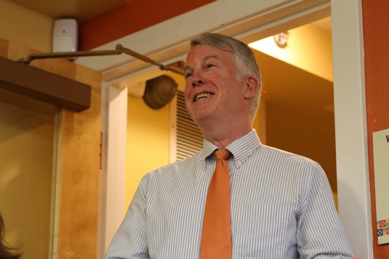 a man in a striped shirt and orange tie