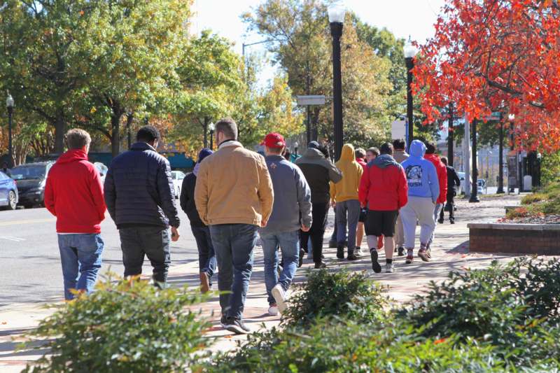 a group of people walking on a sidewalk
