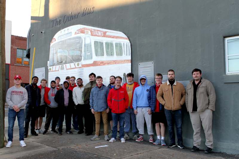 a group of people standing in front of a wall with a picture of a bus