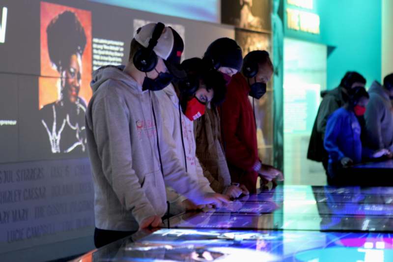 a group of people wearing masks and standing in front of a display