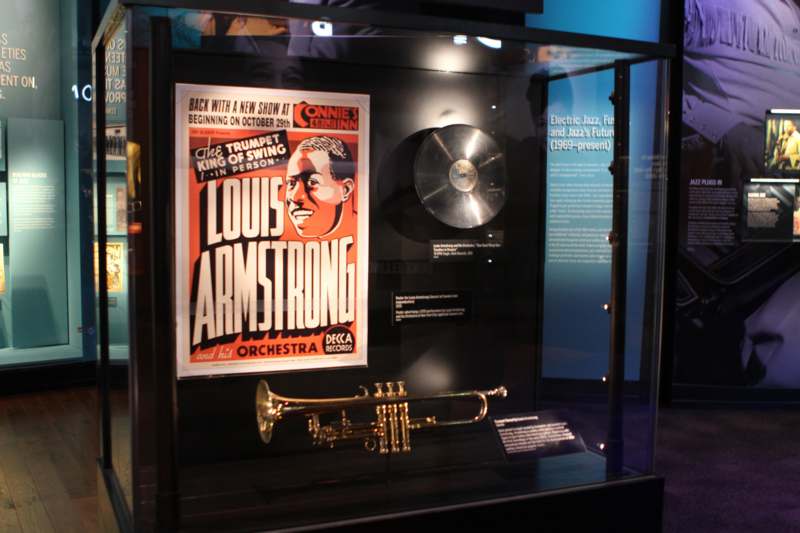 a poster and a trumpet in a glass case