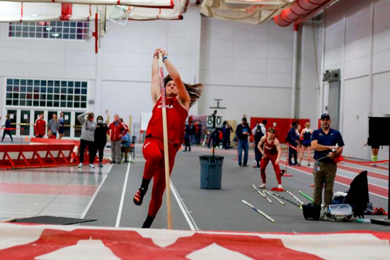 a man in a red uniform holding a pole in a gym