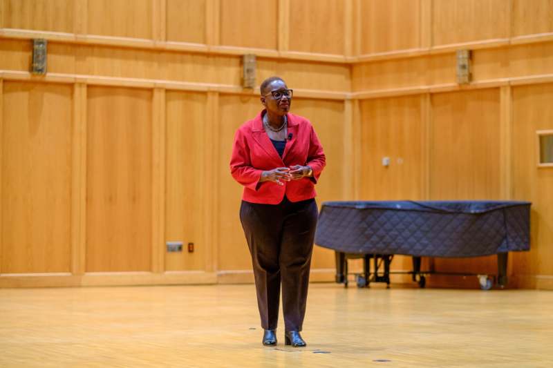 a woman in red jacket and black pants standing on a wood floor