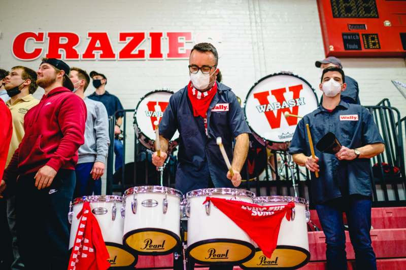 a group of people wearing masks and playing drums