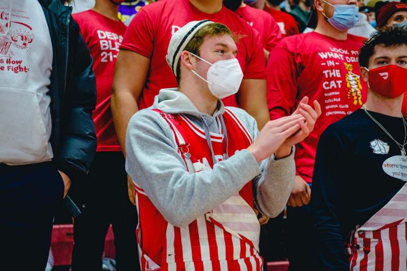 a man wearing a mask and standing in a crowd