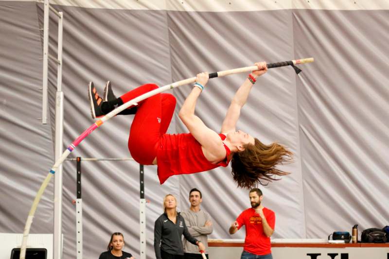 a woman jumping over a pole