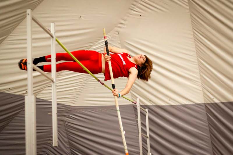 a woman in red outfit jumping over a pole