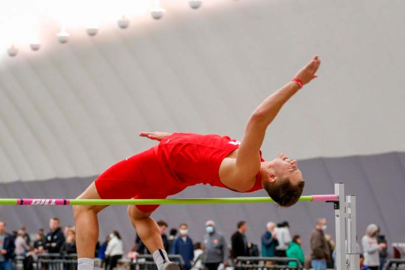 a man in red shirt and shorts doing a high jump