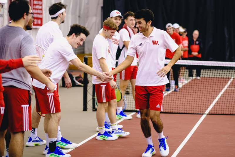 a group of men shaking hands on a tennis court