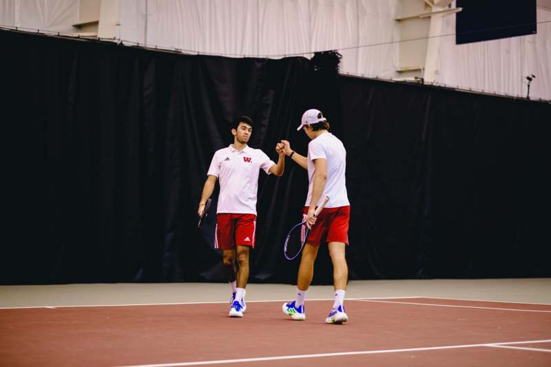 two men shaking hands on a tennis court