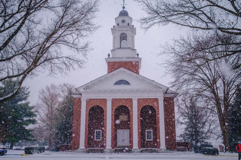 a building with a tower and trees in the snow