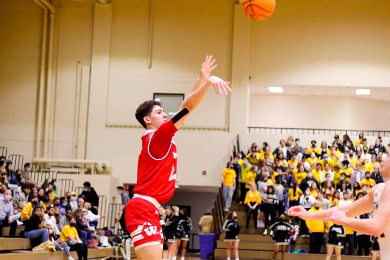 a man in a red jersey jumping to block a basketball