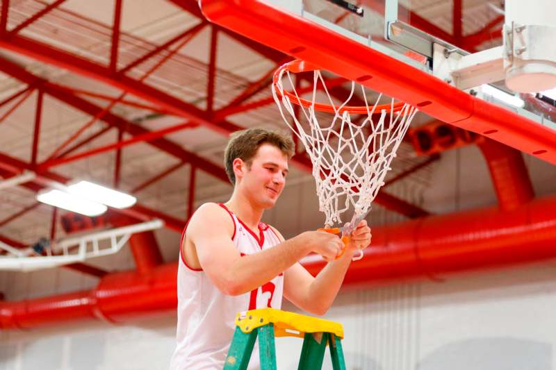 a man on a ladder holding a basketball net