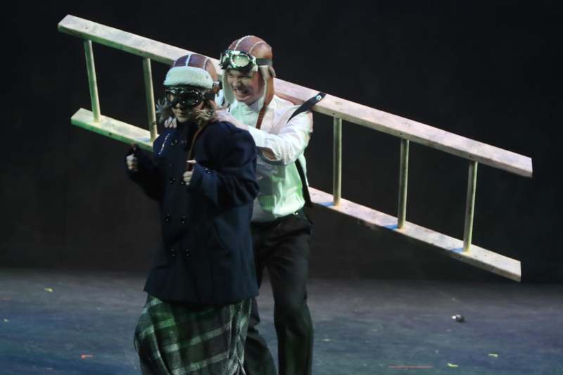 a man and woman wearing goggles and running on stage