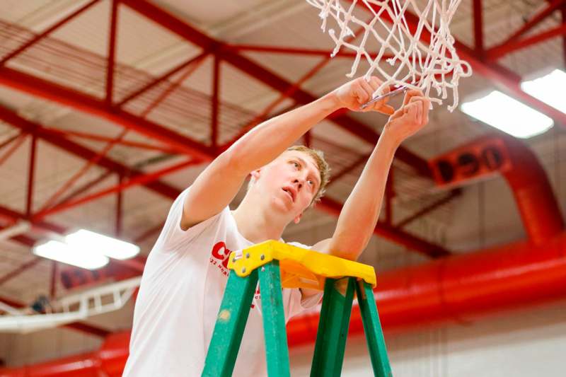 a man on a ladder holding a basketball net