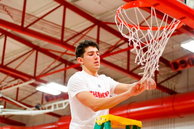a man in a white shirt holding a basketball net