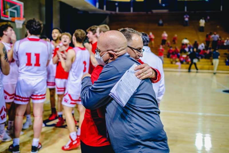 a man hugging another man in a basketball court