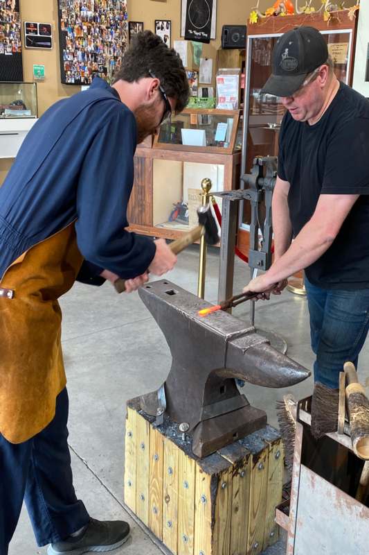 two men working on a metal anvil
