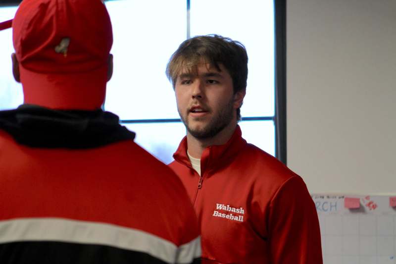 a man in red jacket talking to another man