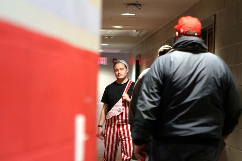 a man in striped overalls walking in a hallway