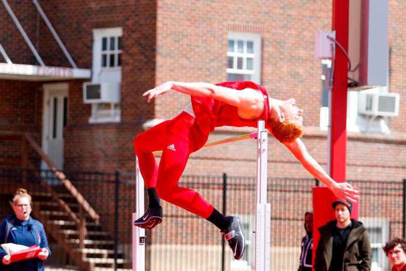 a man in red jumping over a pole