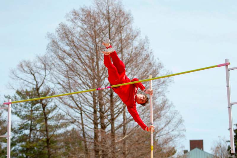a man in red jumps over a pole