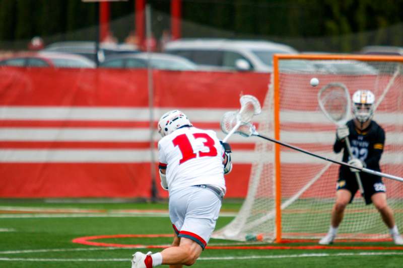 a man in a white uniform playing lacrosse