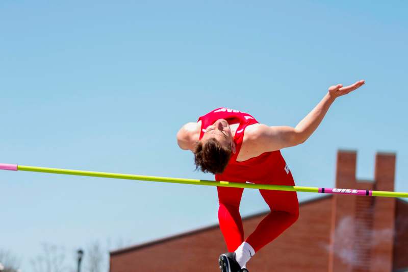 a man in a red uniform jumping over a pole