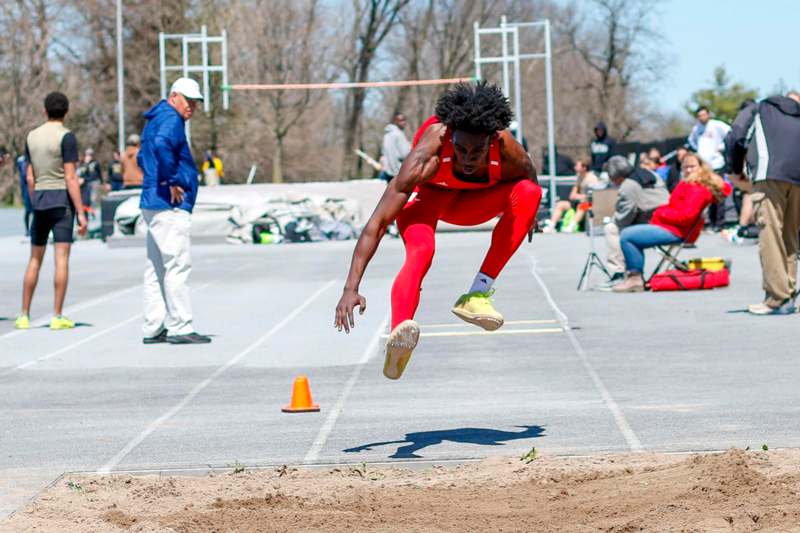 a man in red jumpsuit jumping over a track