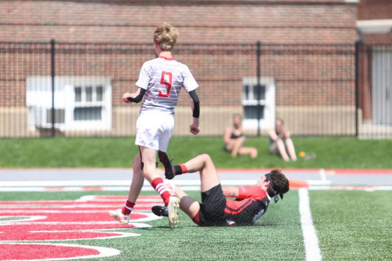 a boy kicking another boy on a field
