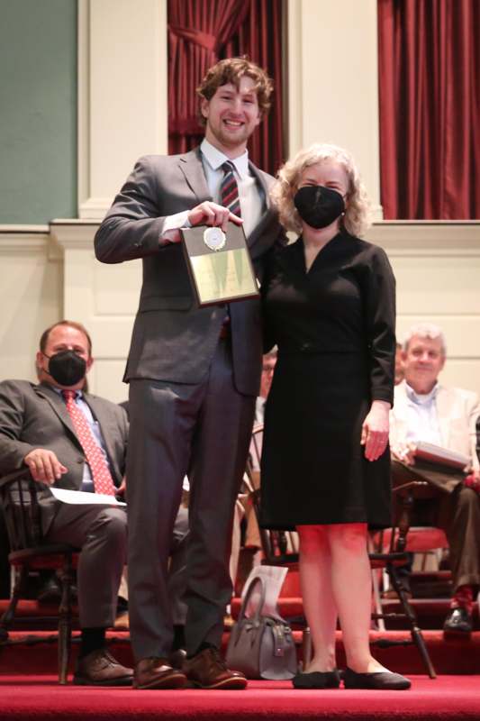 a man holding a plaque with a woman wearing a face mask