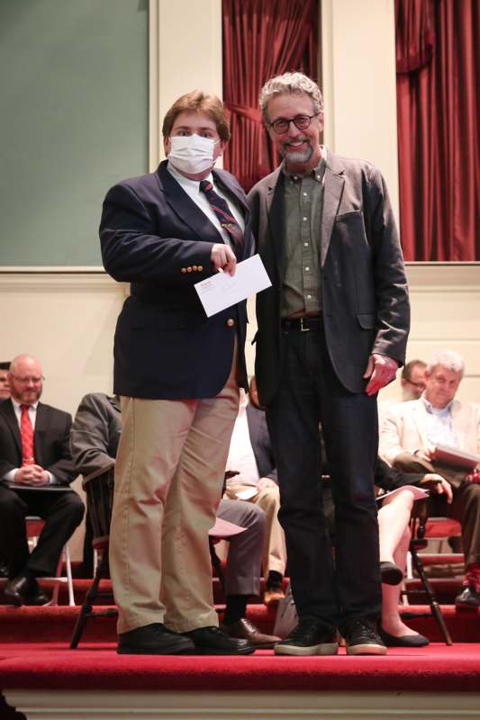 a man wearing a mask and giving a piece of paper to another man