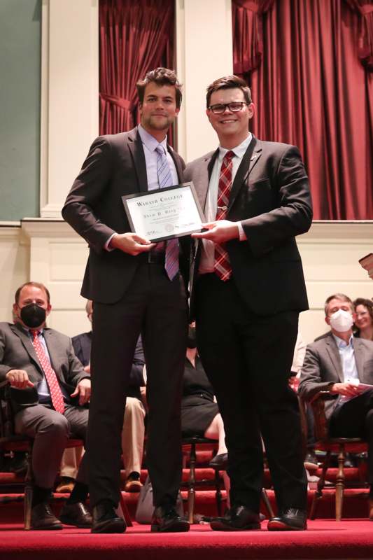 two men in suits holding a certificate