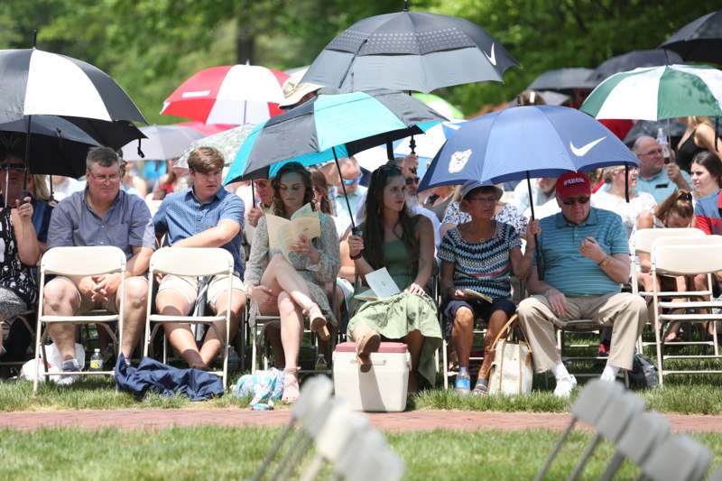 a group of people sitting in chairs with umbrellas