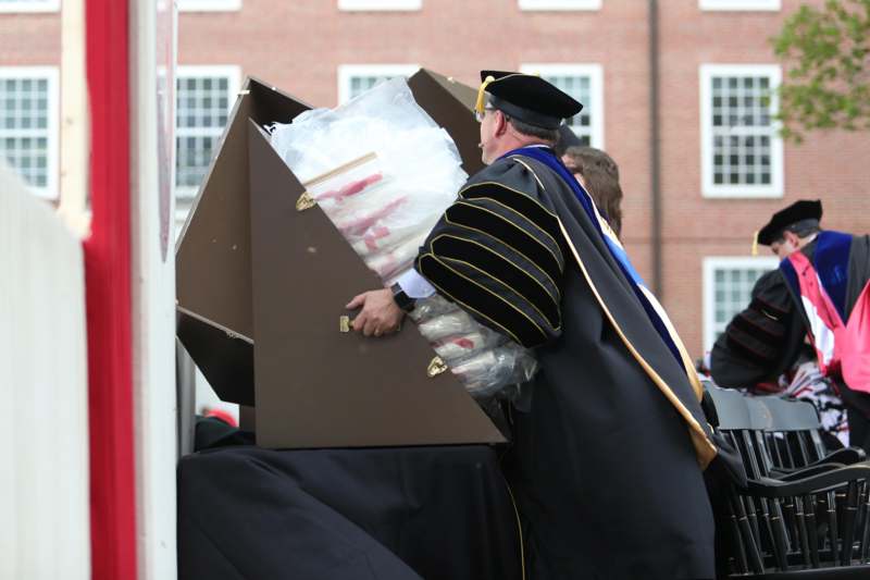 a man in a graduation gown holding a large box