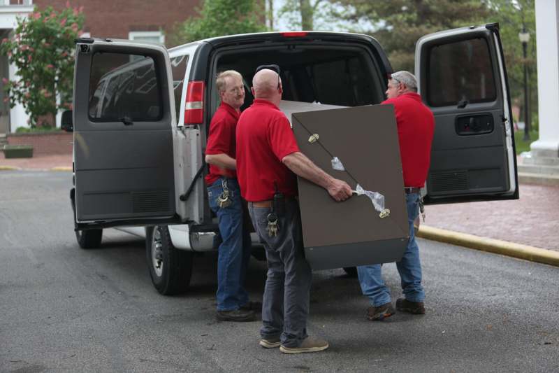 a group of men carrying a large box in the back of a truck