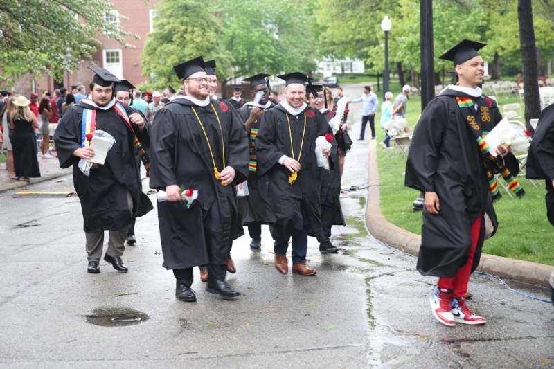 a group of people in graduation gowns and caps walking down a street